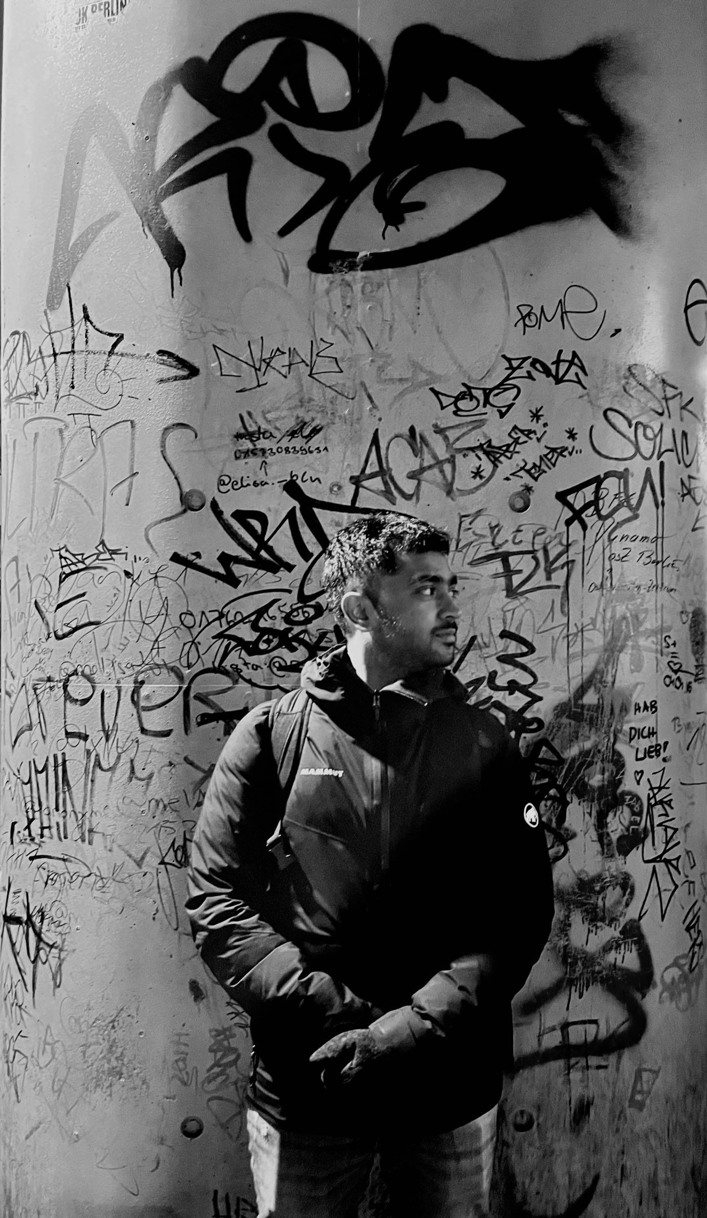 Naveen standing in front of a graffiti-covered concrete pillar